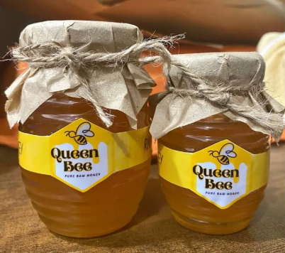Two glass jars of packaged raw pure honey with paper lids tied with twine for local retail sale